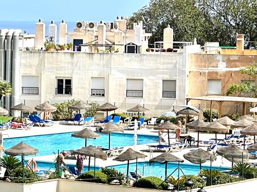 una piscina con sombrillas y sillas y un edificio en LA NOGALERA LUXURY & PLEASURE, en Torremolinos