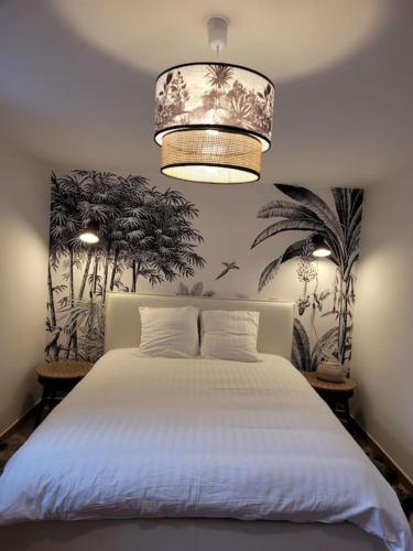 - une chambre avec un lit blanc et un lustre dans l'établissement Le cours Donville, appart neuf à 100m de la mer, à Donville-les-Bains