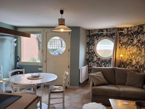 a living room with a couch and a table at Le cours Donville, appart neuf à 100m de la mer in Donville-les-Bains