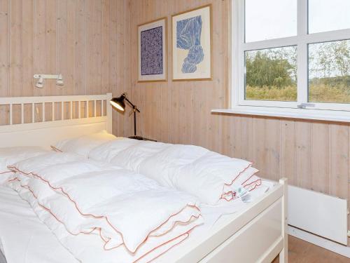 Three-Bedroom Holiday home in Øster Assels 3 في Sillerslev: غرفة نوم بسرير وملاءات بيضاء ونافذة