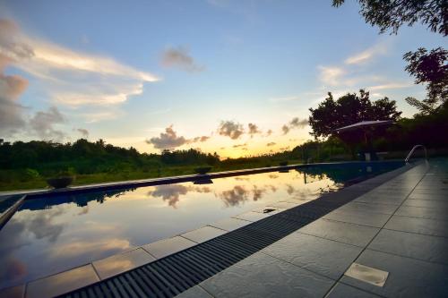 a pool with a reflection of the sky in the water at Jungle Villa in Induruwa