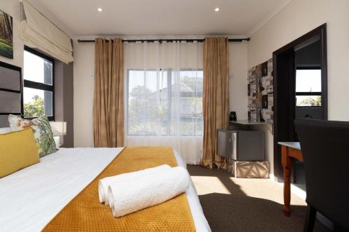 Un dormitorio con una cama con un escritorio y una ventana. en Casa Milner Guest House, en Ciudad del Cabo