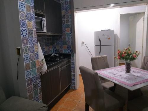 a small kitchen with a table and a refrigerator at Pequeno, más aconchegante in Itapema