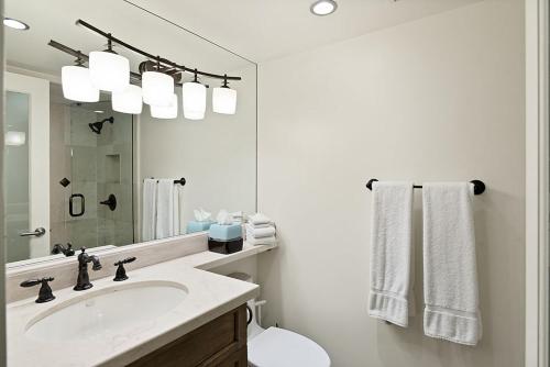 a white bathroom with a sink and a mirror at Chateau Eau Claire 9, Newly Renovated Condo with River Views, Hot Tub, Pool, Fitness Center Access in Aspen