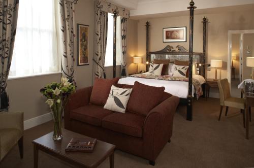 a bedroom with a bed and a couch and a chair at The Bull Hotel; Sure Hotel Collection by Best Western in Peterborough