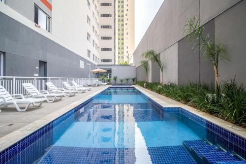 uma piscina com espreguiçadeiras e um edifício em Canal do Anfitrião | Studios delicinhas em São Paulo