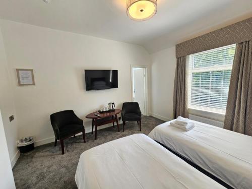 a hotel room with two beds and a table and chairs at ABBEY HOTEL in Stafford
