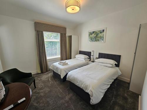 ein Hotelzimmer mit 2 Betten und einem Stuhl in der Unterkunft ABBEY HOTEL in Stafford