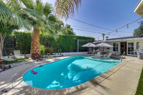 a swimming pool with a palm tree next to a house at Stagecoach Home Base! Palm Desert Casita with Pool in Palm Desert