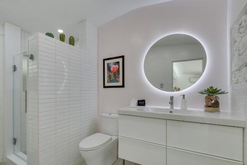 een witte badkamer met een toilet en een spiegel bij Palm Desert Casita with Pool 5 Blocks to El Paseo in Palm Desert