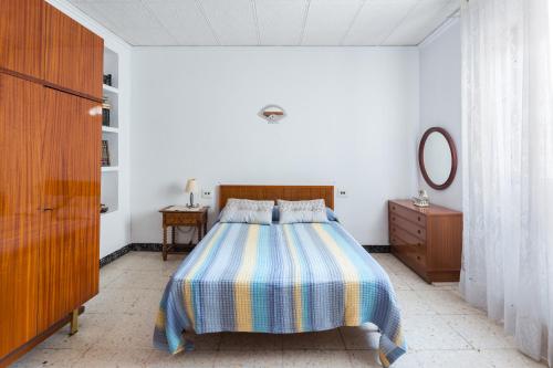 een slaapkamer met een bed, een dressoir en een spiegel bij La Matea in Llaurí