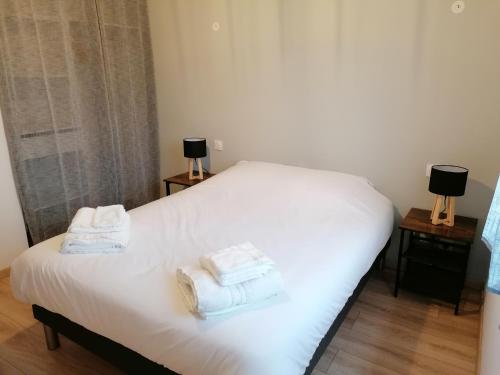 une chambre avec un lit blanc avec des serviettes dessus dans l'établissement Les Lodges du Bousquet, à Tamniès