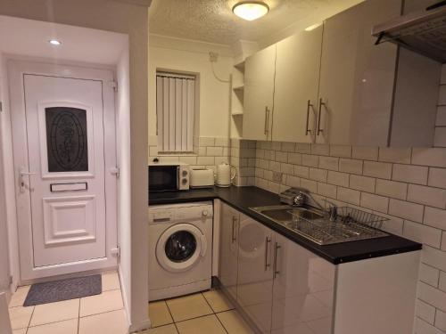 a kitchen with a sink and a washing machine at Opera Home in Peterborough