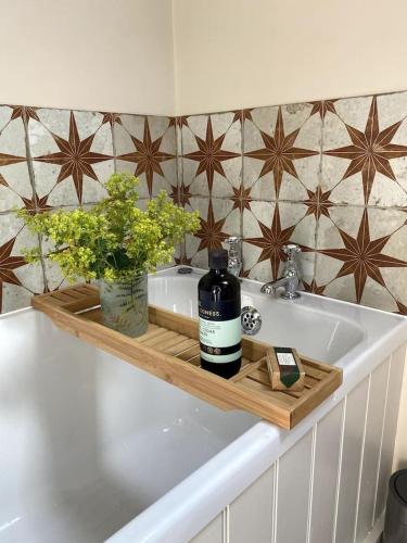 lavabo en el baño con una botella de vino en una bandeja de madera en The Most Magical Woodshed, en Daventry