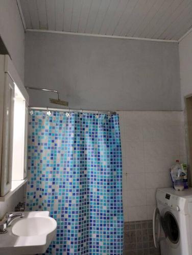 baño con cortina de ducha azul y lavamanos en casa en Gualeguaychú en Gualeguaychú