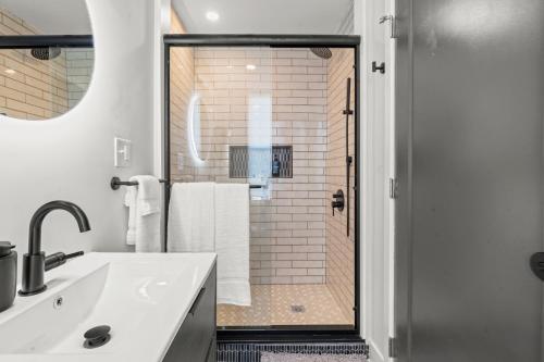 a bathroom with a shower with a white sink and a mirror at 1 BR Passyunk Ave Stunner- Perfect Location in Philadelphia
