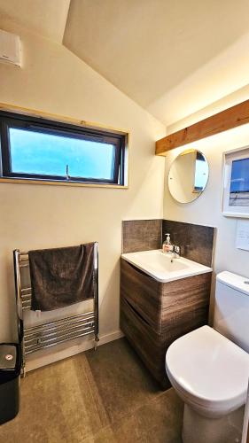 Un baño con lavabo, inodoro y ventana. en Eagle's Nest Connemara and Westport, en Westport