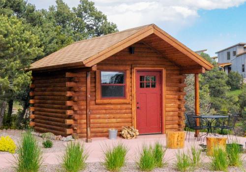a small log cabin with a red door at Royal Gorge Cabins in Buckskin Joe