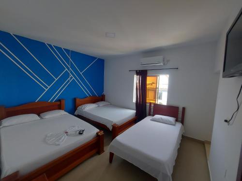 a room with three beds and a tv in it at HOTEL LONDON Con Parqueadero in Aguachica