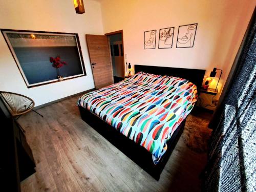 um quarto com uma cama com um edredão colorido em Chambre dans une maison d'hote em Liège