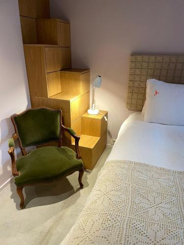 a bedroom with a bed and a green chair at toctoctoc lisboa in Lisbon