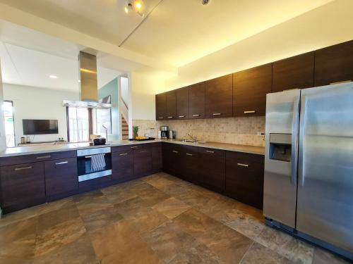 a large kitchen with wooden cabinets and a stainless steel refrigerator at Tuscany Residence Aruba in Palm-Eagle Beach