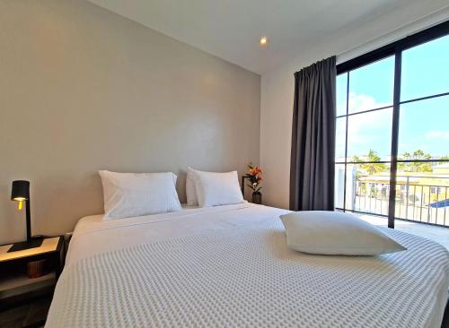 a bedroom with a large white bed with a large window at Tuscany Residence Aruba in Palm-Eagle Beach