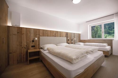 two beds in a bedroom with wood paneling at Living Miramor in Racines