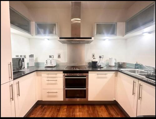 a kitchen with white cabinets and stainless steel appliances at Central London Large 1 Bed flat with Balcony in London