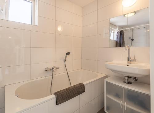 a bathroom with a bath tub and a sink at Aanloop 22 in Domburg