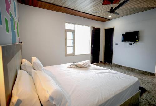 a bedroom with a large bed with pillows and a tv at Hotel Pleasing Pines in Dagshai