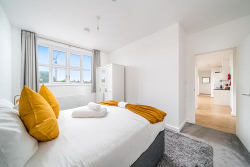a white bedroom with a large bed with yellow pillows at Luxury 2 Bedroom Apartment Free Parking, Netflix, Sleeps 6 in Watford
