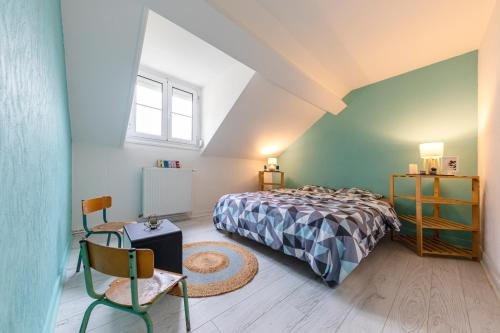 um quarto com uma cama e uma cadeira num sótão em La Maison du Centre GOUVIEUX - CHANTILLY em Gouvieux