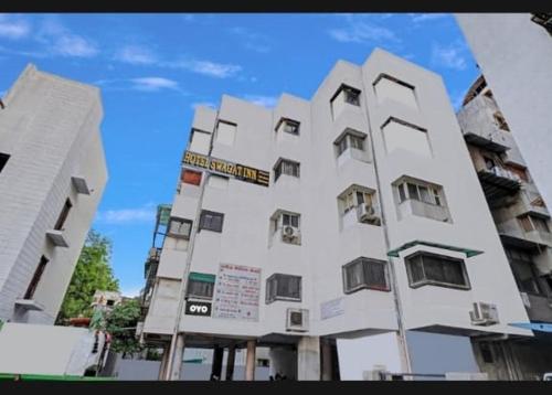 アーメダバードにあるhotel swagat innの正面に看板がある大きな白い建物