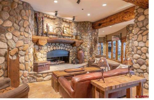 a large stone fireplace in a living room with leather furniture at Grand Lodge in Crested Butte