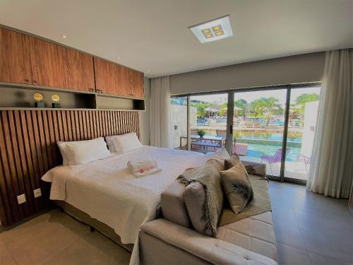 1 dormitorio con cama, sofá y piscina en ILE DE PIPA Oásis - By Almare Flats, en Pipa