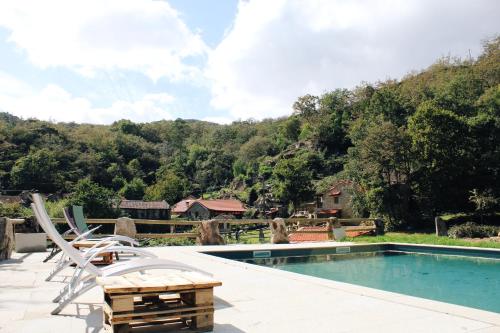 a swimming pool with two chairs and a table at Aldeia de Pontes - Castro Laboreiro in Castro Laboreiro