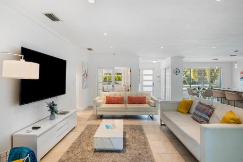 a living room with two couches and a tv at Exclusive Miami House: Your Private Pool Paradise in Biscayne Park