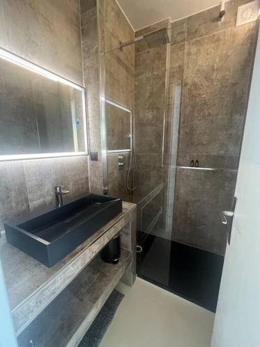 une salle de bain avec un lavabo et une douche dans l'établissement Le Lodge, à Martigues