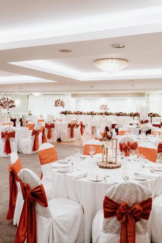 a banquet hall with white tables and chairs with bows at Bushtown Hotel & Spa in Coleraine