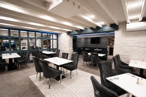 a dining room with tables and chairs and windows at Bushtown Hotel & Spa in Coleraine