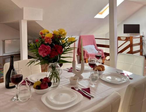 uma mesa com pratos e copos de vinho e flores em Casuta cu amintiri em Câmpulung