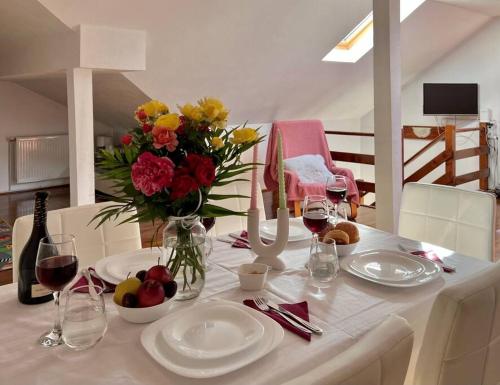 a table with plates and glasses of wine and flowers at Casuta cu amintiri in Cîmpulung