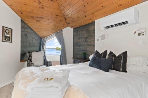 1 dormitorio con cama blanca y techo de madera en Quinte Haven - Waterfront slice of paradise en Carrying Place