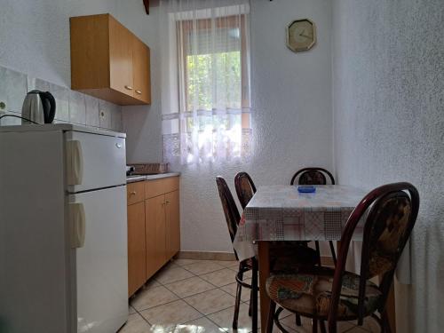 eine Küche mit einem Tisch mit Stühlen und einem weißen Kühlschrank in der Unterkunft Gjorgji Apartments 68a in Ohrid