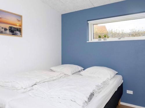 ein Schlafzimmer mit einem Bett mit blauer Wand und einem Fenster in der Unterkunft Holiday home Vinderup XXVII in Vinderup