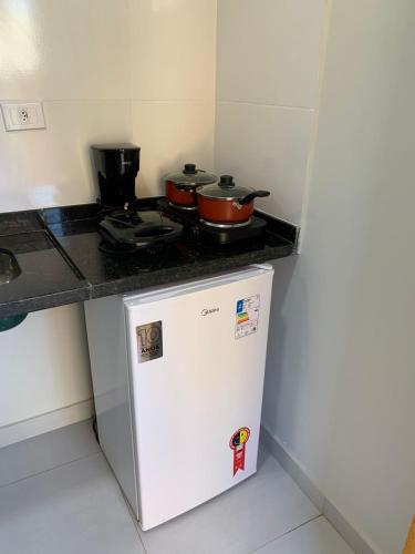 - une cuisine équipée d'une cuisinière et de 2 casseroles au-dessus du réfrigérateur dans l'établissement Lavínia loft 5, à Búzios