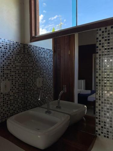 two sinks in a bathroom with a window and a mirror at Suites Vossoroca in Alto Paraíso de Goiás