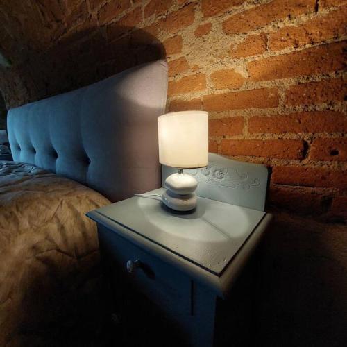 a lamp on a night stand next to a bed at Istanti - Rosmarino in Costigliole Saluzzo