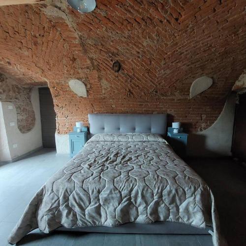 a bedroom with a large bed in a brick wall at Istanti - Rosmarino in Costigliole Saluzzo